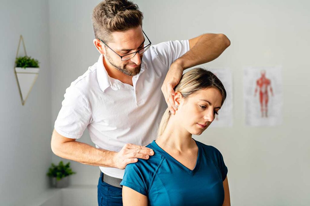 Person receiving a gentle chiropractic adjustment on their lower back in a medical office setting.